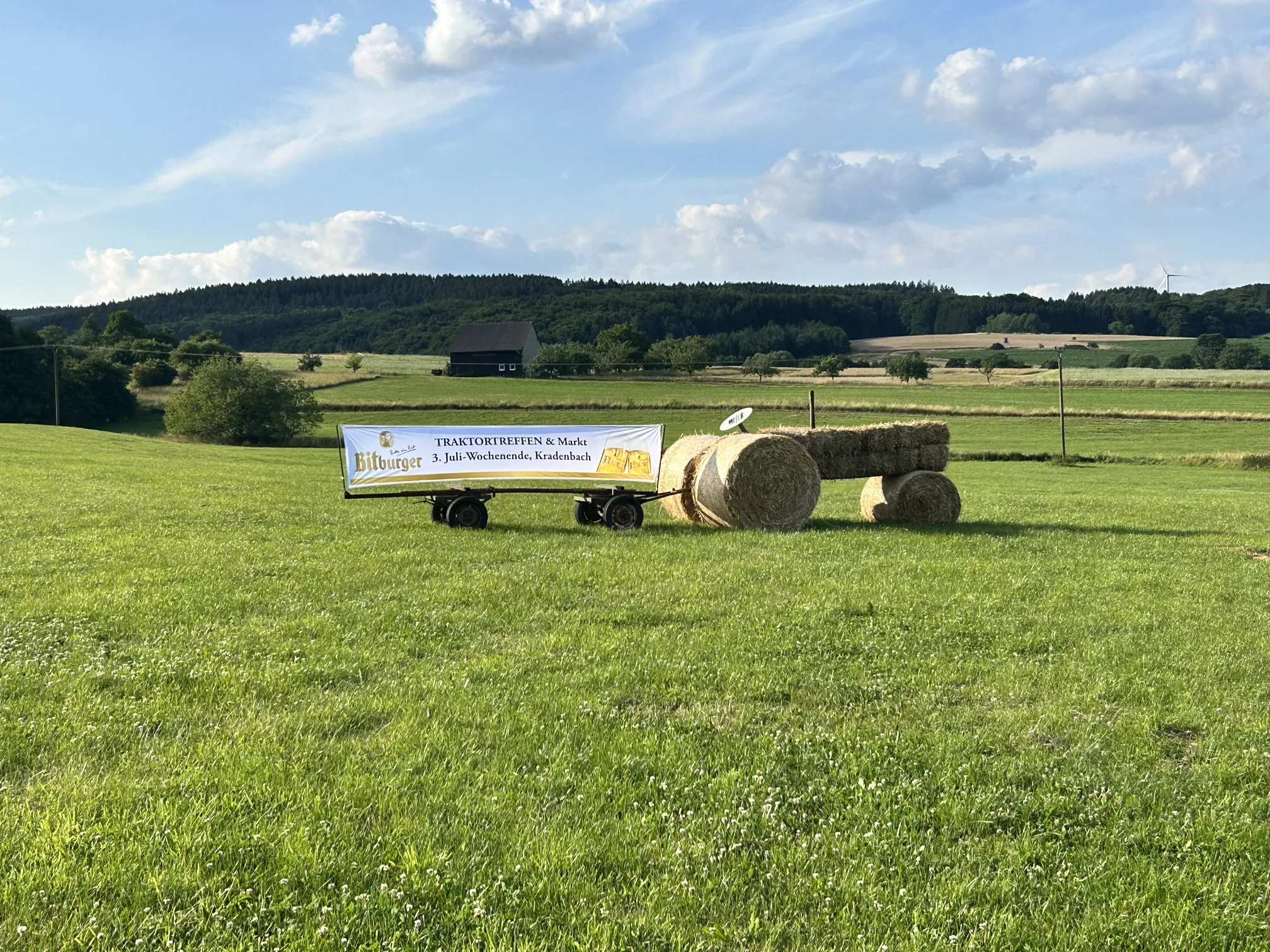 Traktor mit Anhänger am Dorfanfang mit Plakat Traktor mit Anhänger am Dorfanfang mit Plakat
